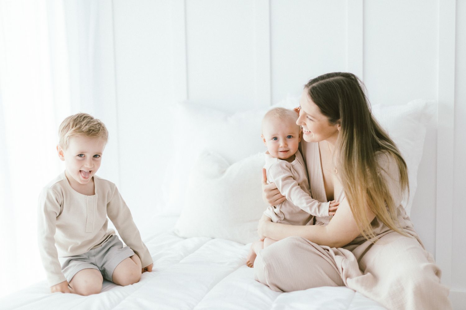 Family having tender moments together on white bed.