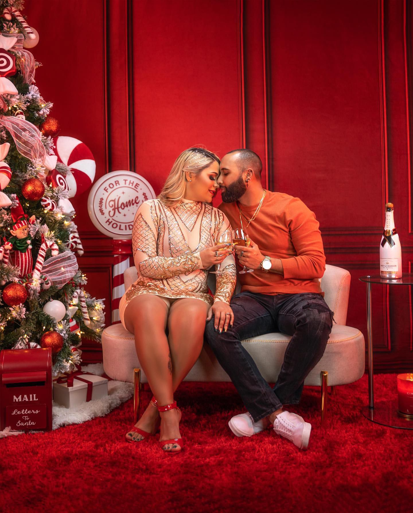 Festive holiday portrait with Christmas tree, peppermint decorations, and red wall backdrop.