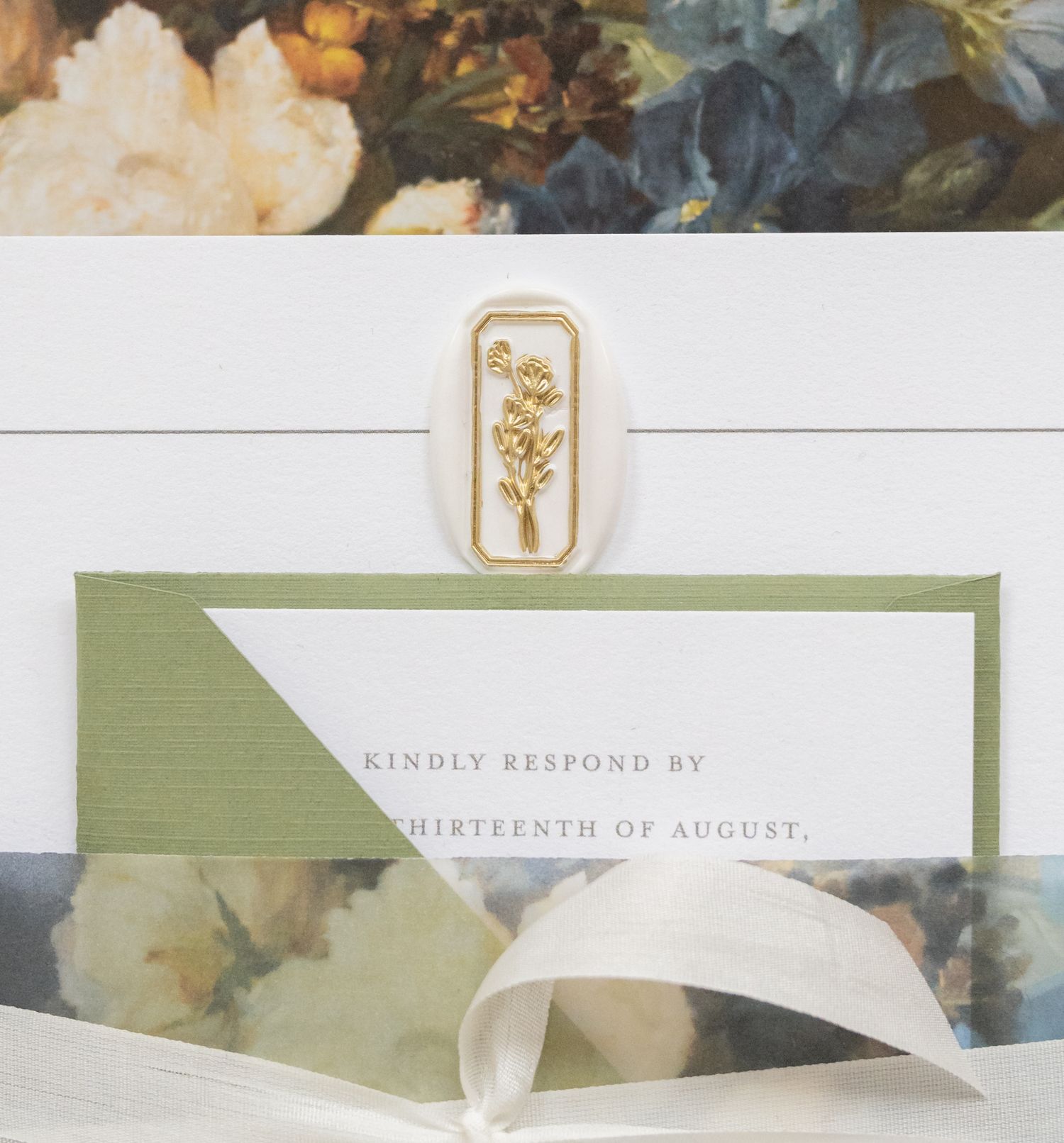 Wedding RSVP card with gold floral seal and sage green accent on white paper.