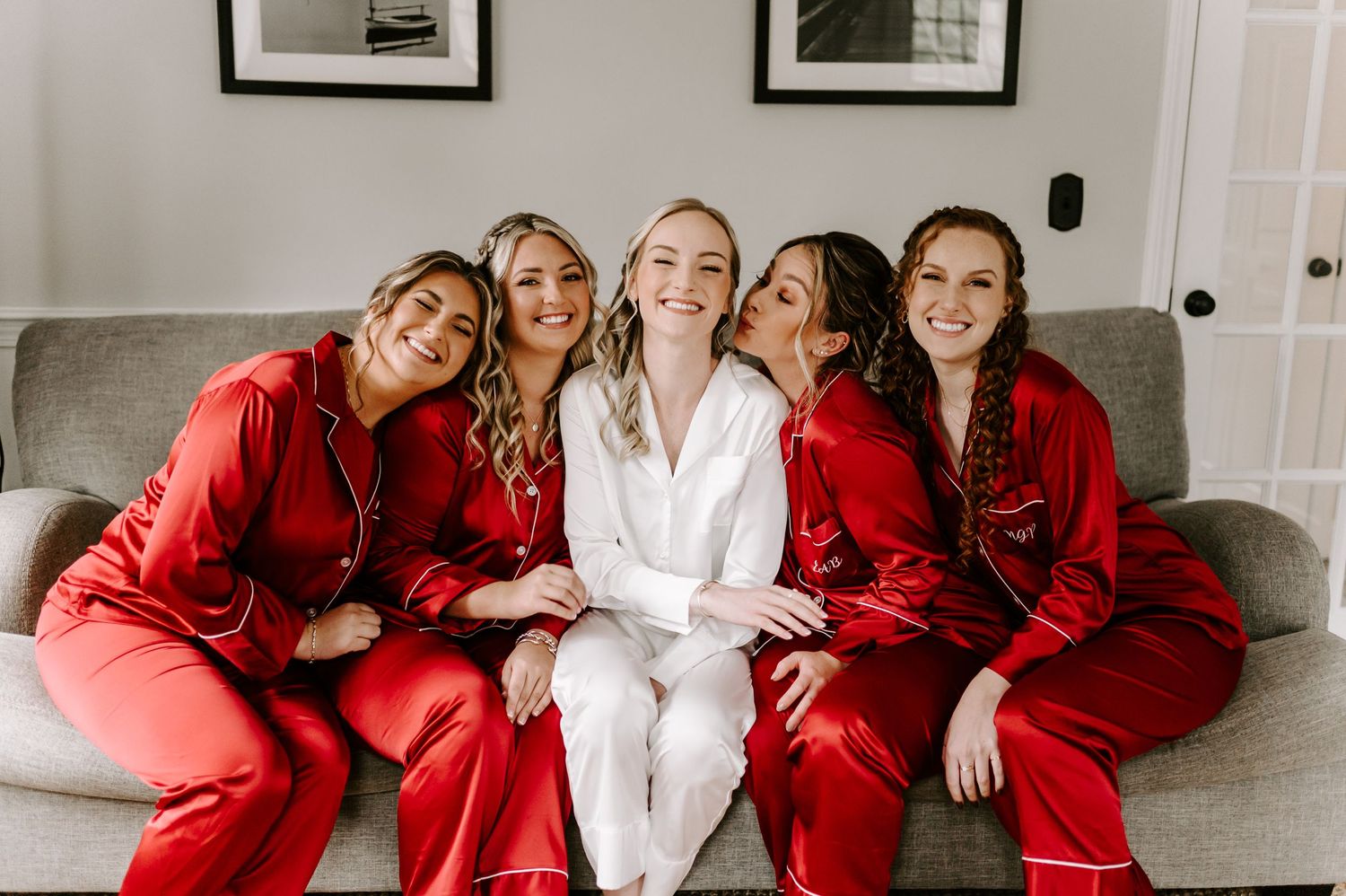 Group of women in red robes sitting together with one in white.