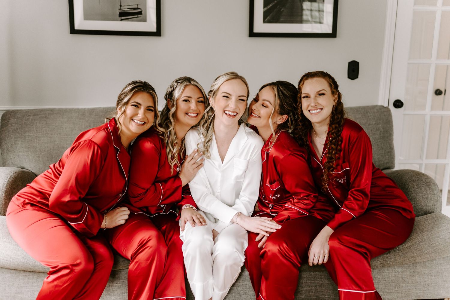 Bridesmaids in red robes laughing with bride in white robe.