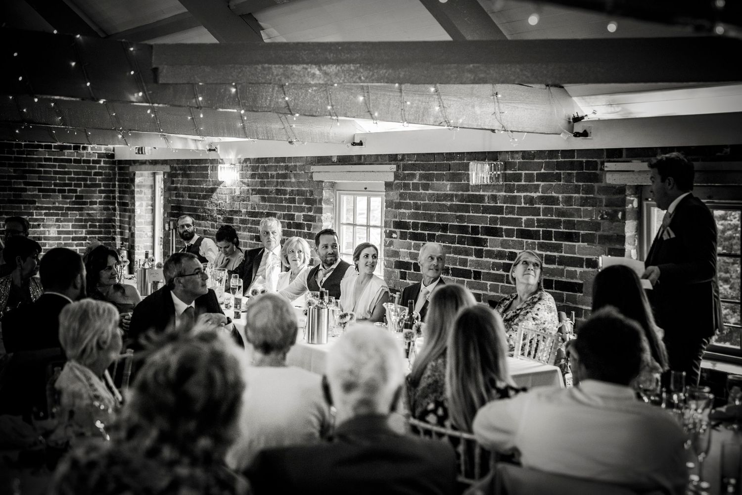 Black and white panoramic view of a wedding reception venue with guests seated at tables.