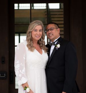 A newlywed couple smiles together in formal wedding attire.