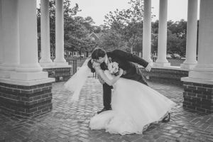 Black and white romantic dip pose between classic white columns.