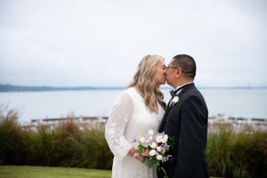 Bride and groom share an intimate moment with waterfront view in background.