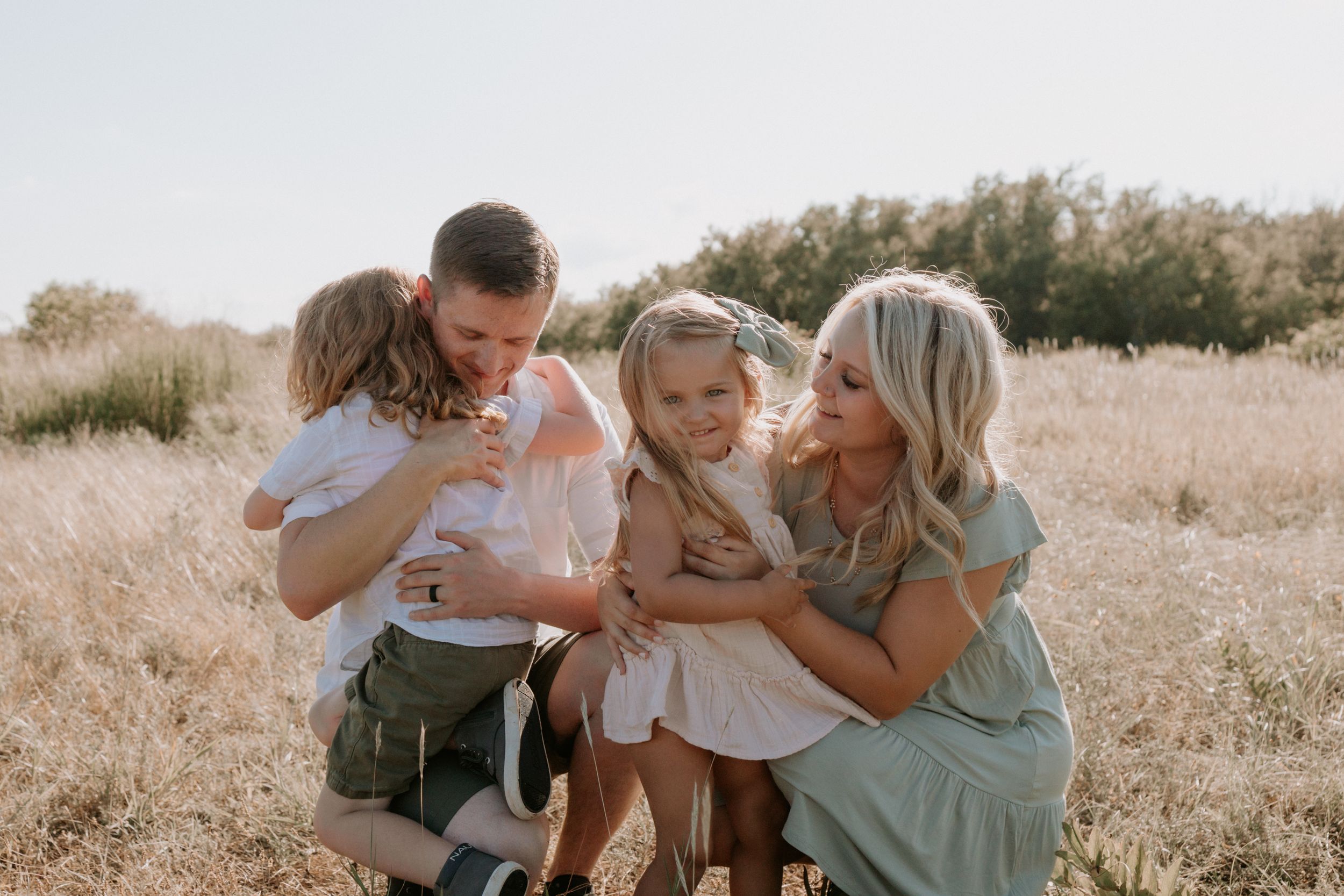 A family shares tender moments together in a sunlit golden field.