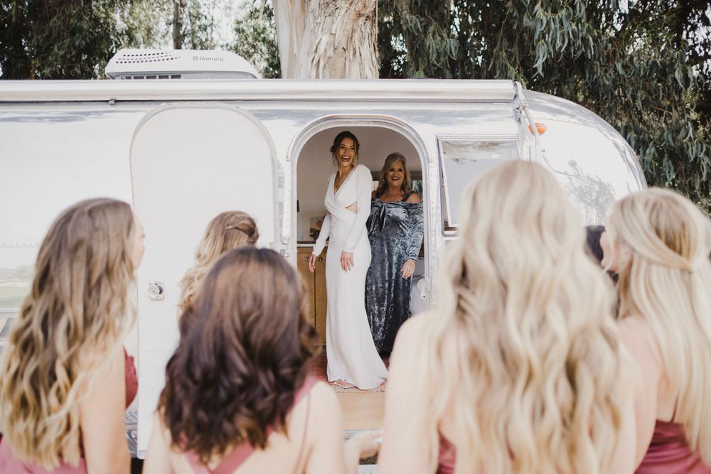 Wedding party members in burgundy dresses share joyful moments together outdoors.