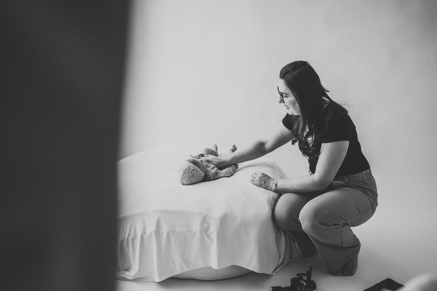 Photographer capturing a newborn session in the studio, adjusting lighting and setting up for the perfect shot – behind-the-scenes