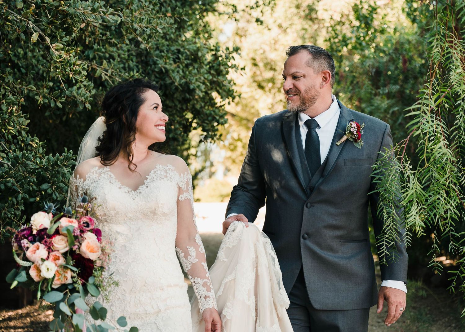 A romantic wedding portrait in a garden setting with the couple holding hands and smiling.