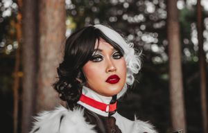 A stylized portrait featuring red lipstick and black and white hair styling against a forest backdrop.