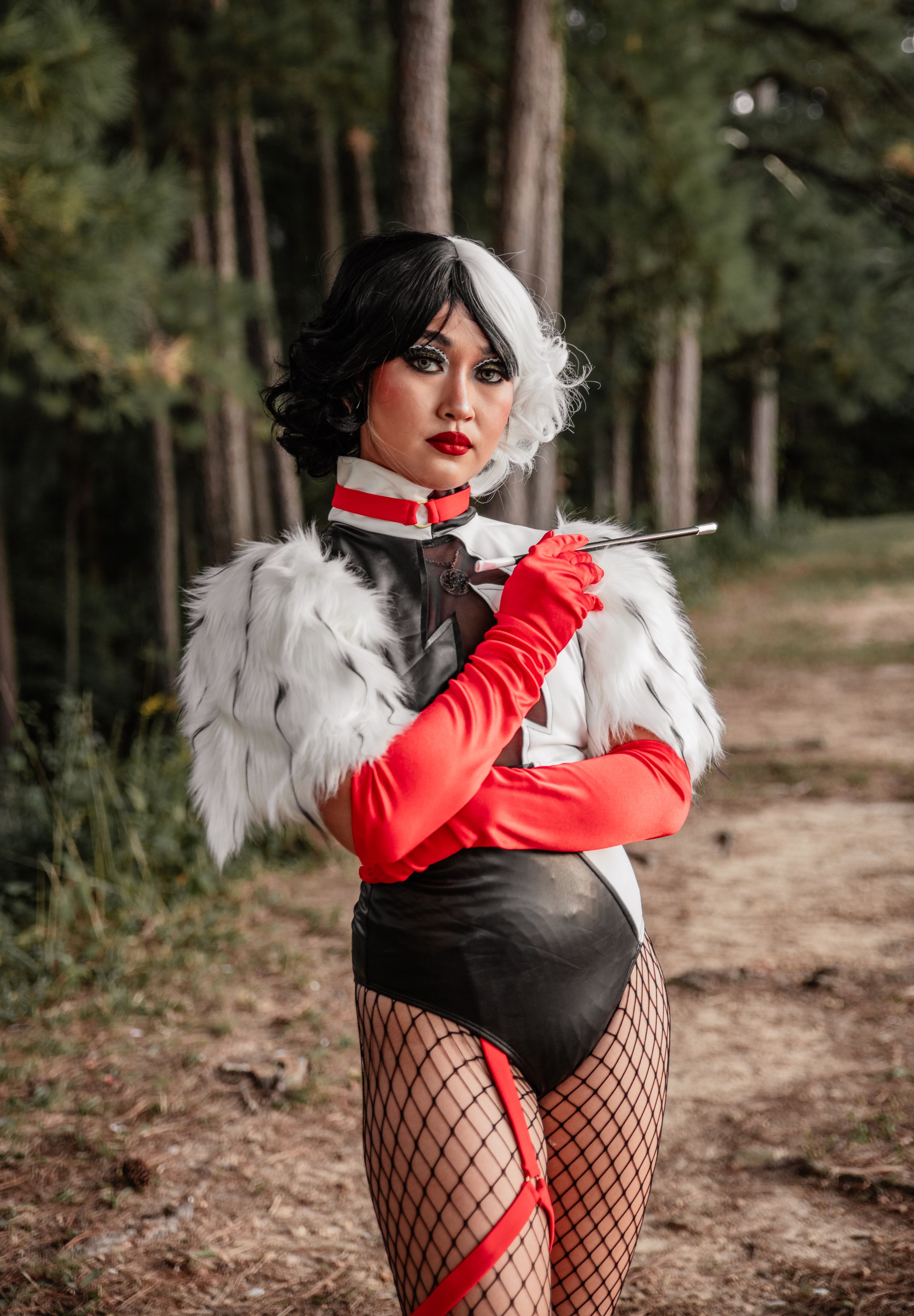 A theatrical costume photoshoot featuring red gloves and white feathers in a wooded setting.