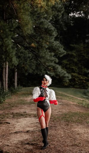 A dramatic pose in fishnet stockings and red costume elements on a forest path.