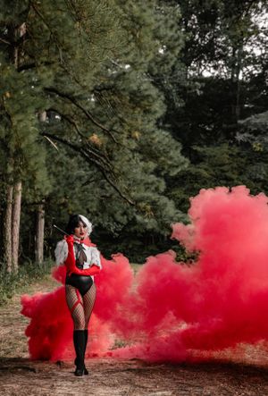 Dramatic forest photoshoot with red smoke bomb creating an ethereal atmosphere.