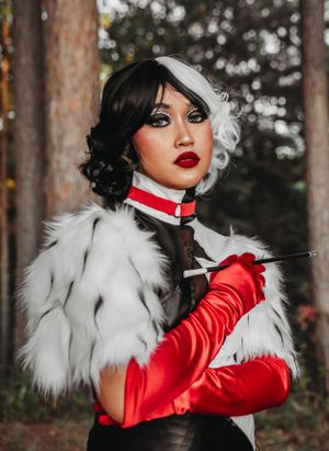 A glamorous costume featuring white fur, red gloves, and dramatic makeup in a forest setting.