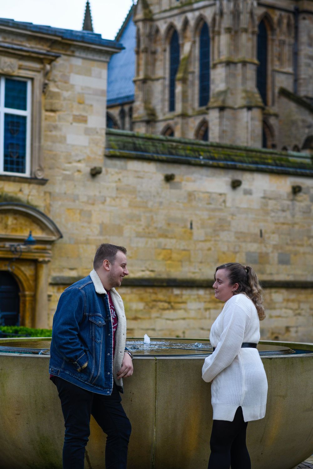 Couple standing in front of historic stone church architecture during engagement shoot.