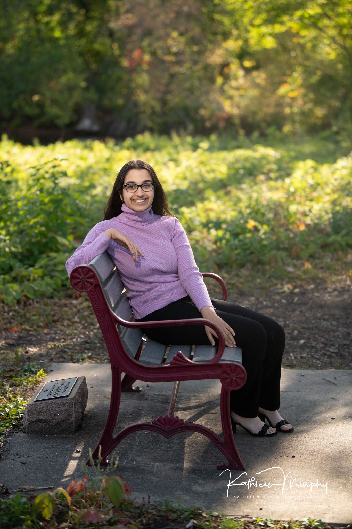 senior student girl sitting on a park bench posing for senior portraits