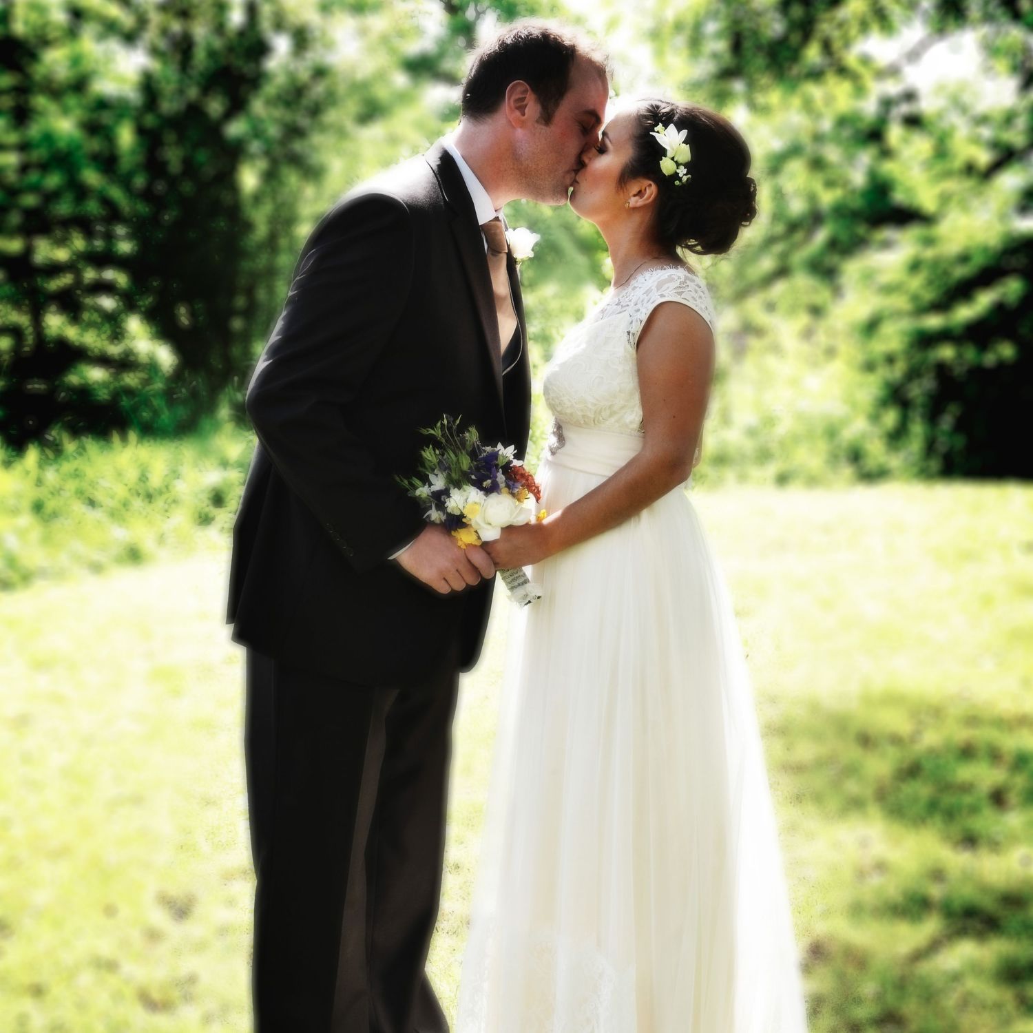 A romantic outdoor wedding moment captured as newlyweds share a kiss in a garden setting.