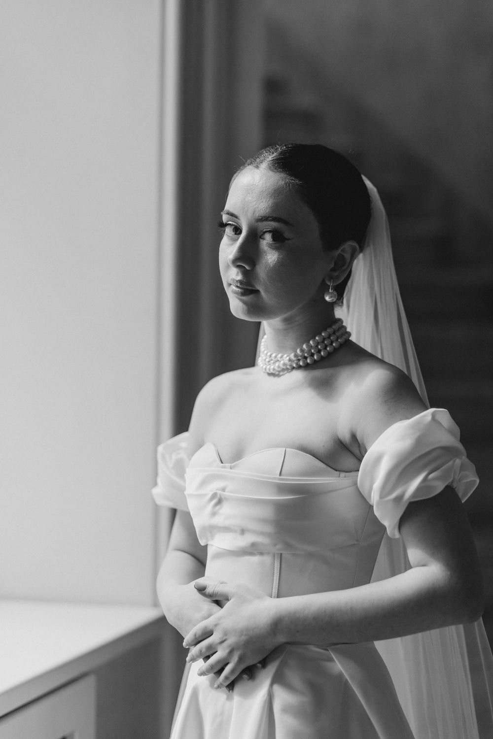 Classic bridal portrait featuring an off-shoulder wedding gown with pearl necklace.