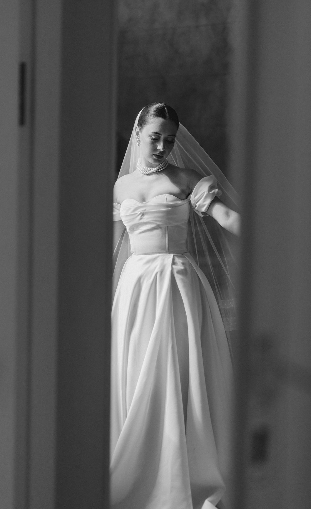 Black and white bridal photo showing structured wedding dress with pleated skirt.