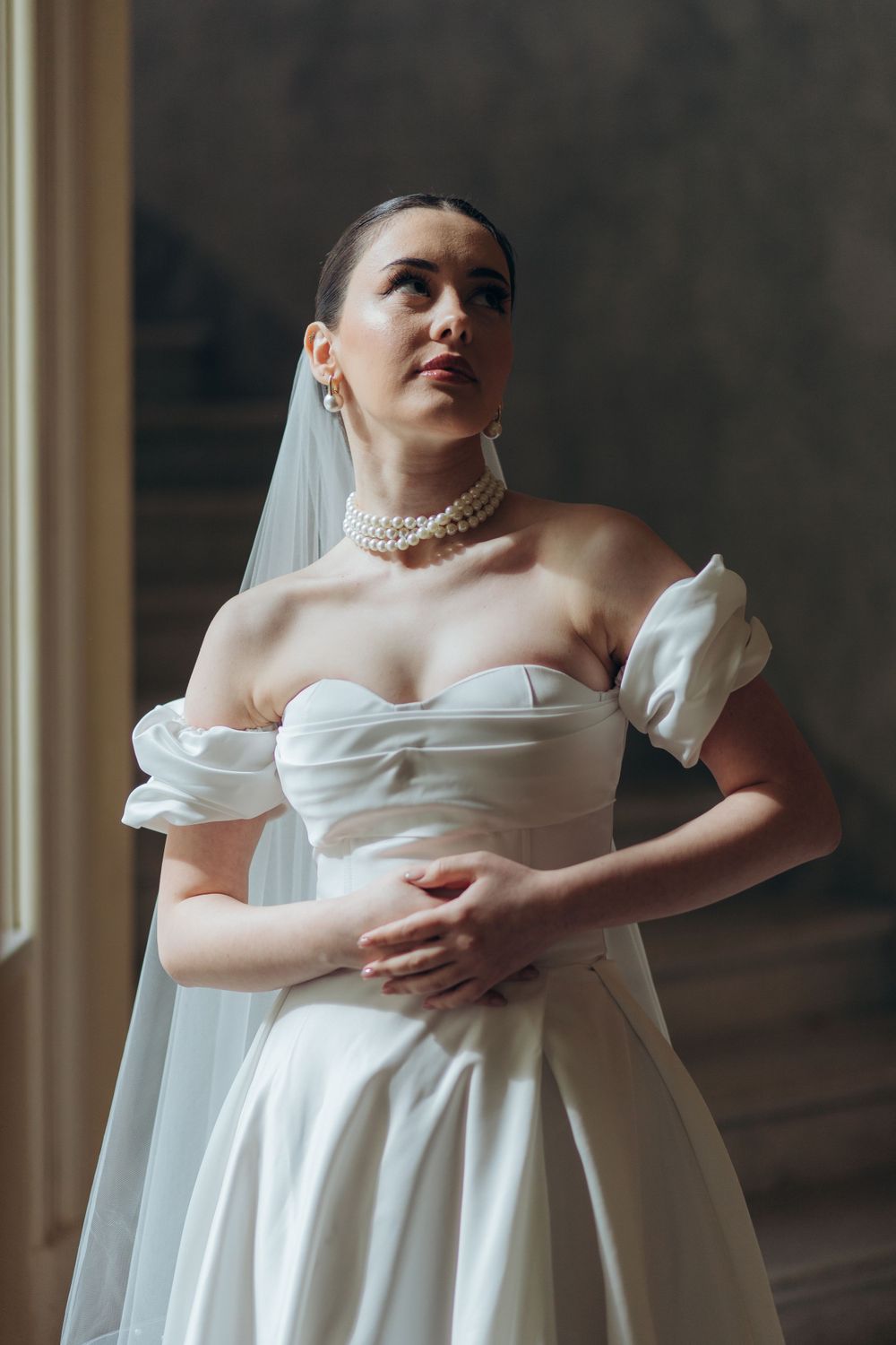 Modern bridal portrait showcasing structured bodice and pearl accessories.