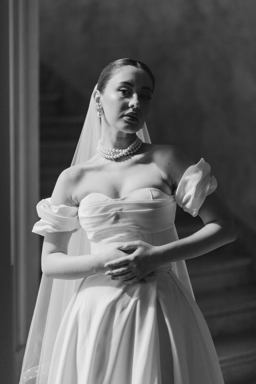 Timeless black and white bridal portrait with pearl necklace and structured bodice.