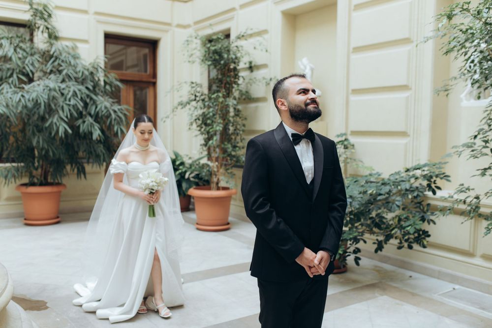 First look moment between bride and groom in courtyard with potted plants.