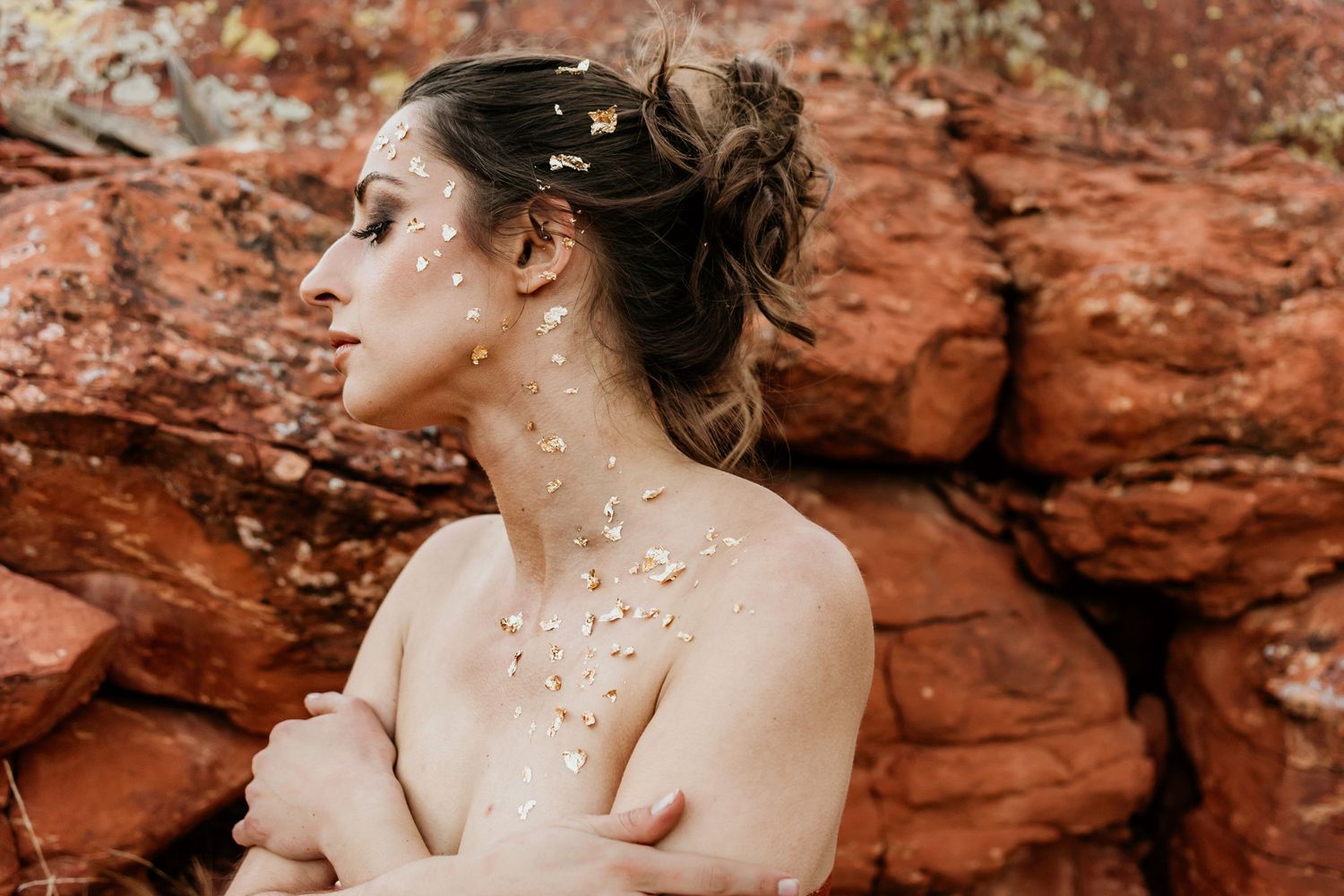 Artistic portrait with glitter details against red rock formation.