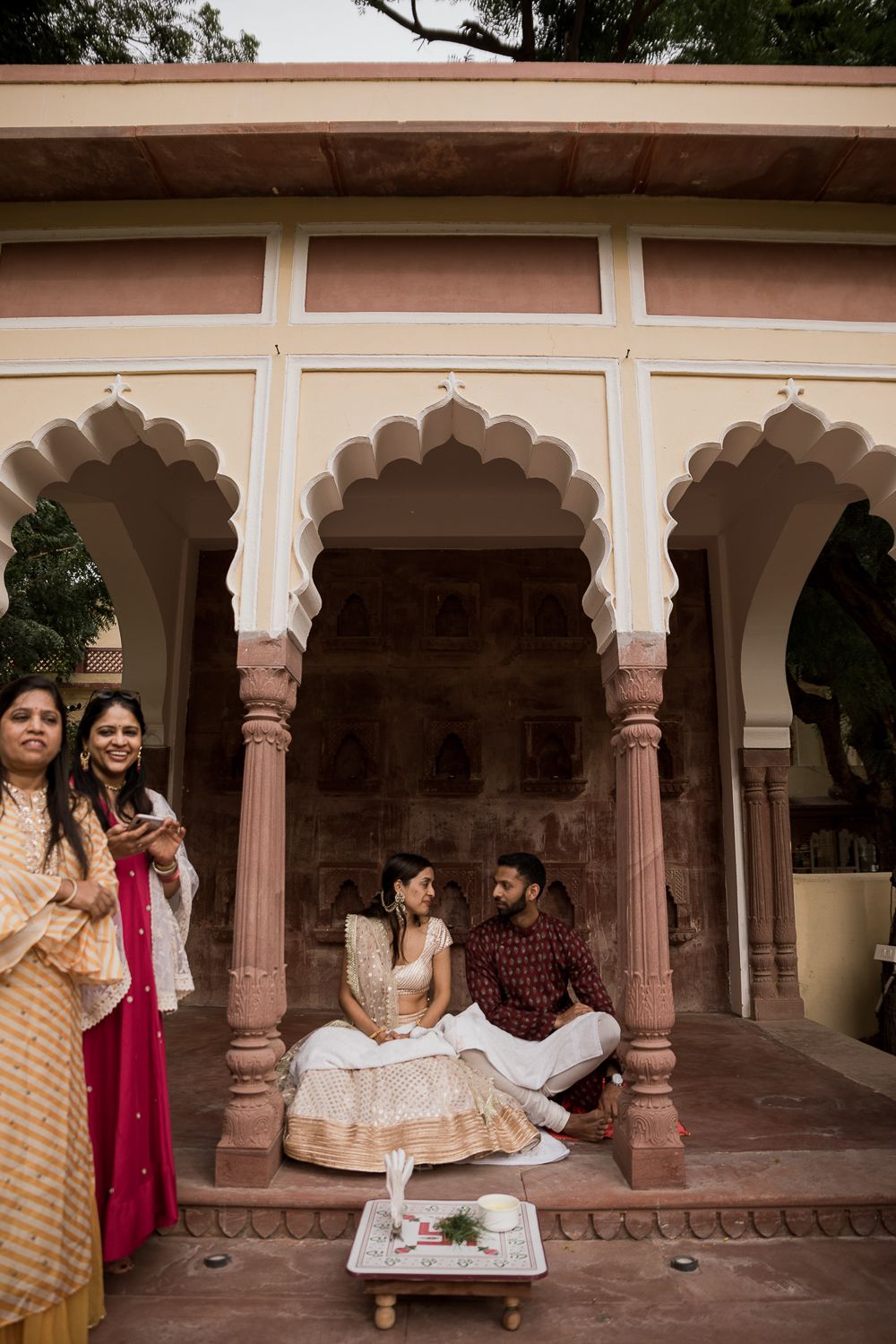 A photograph of a bride and groom under traditional Rajasthani architecture