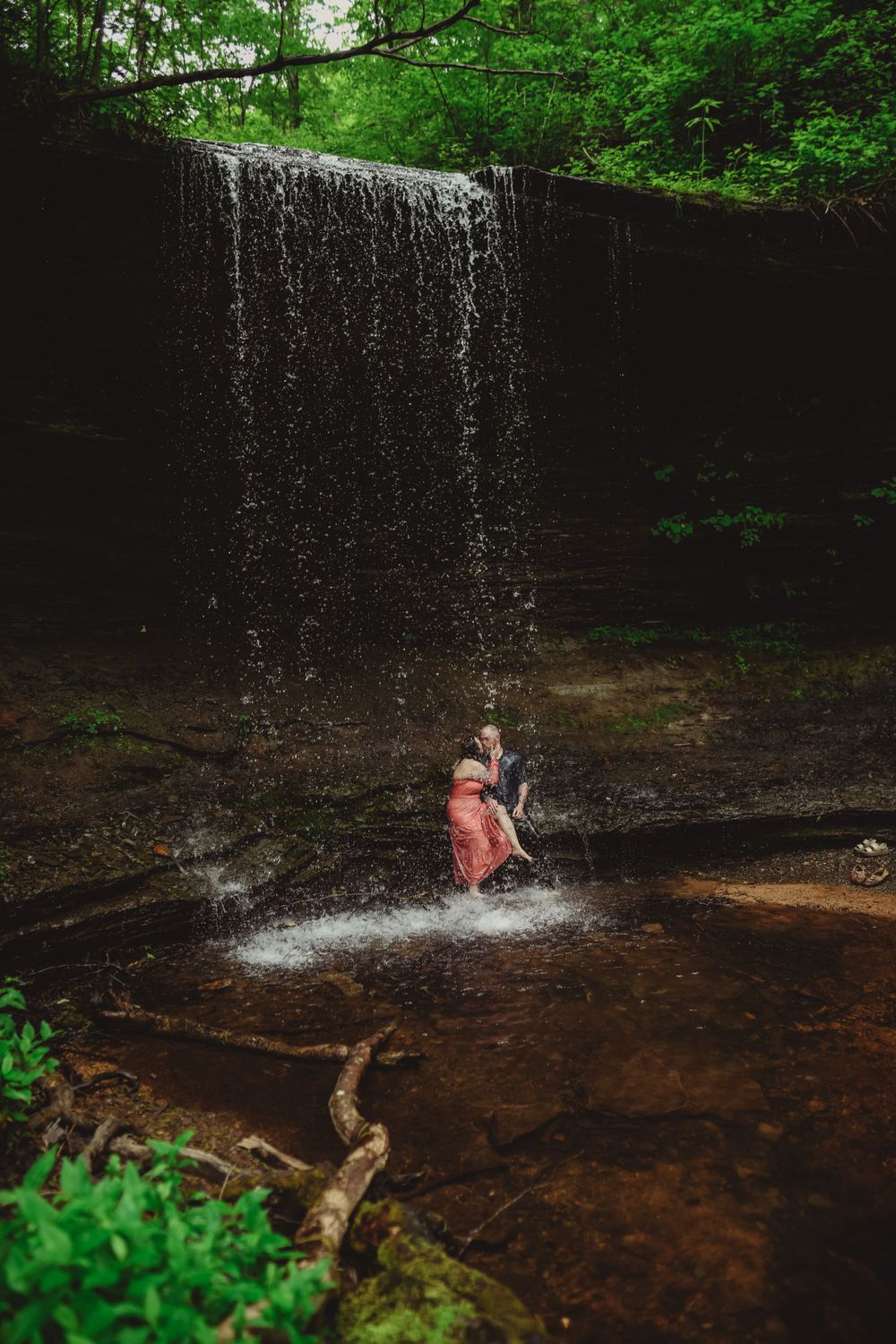 A waterfall creates a magical backdrop for an intimate forest photoshoot.