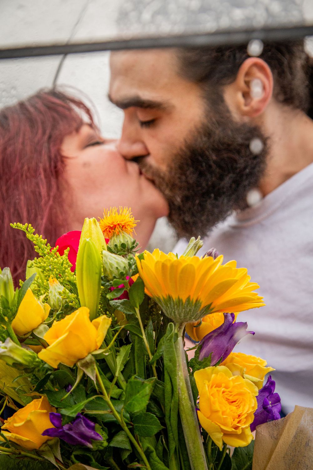 A bouquet of yellow sunflowers and roses frames an intimate moment.