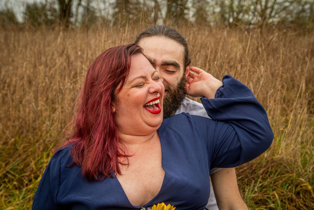 A joyful couple sharing a candid moment in a field of tall golden grass.