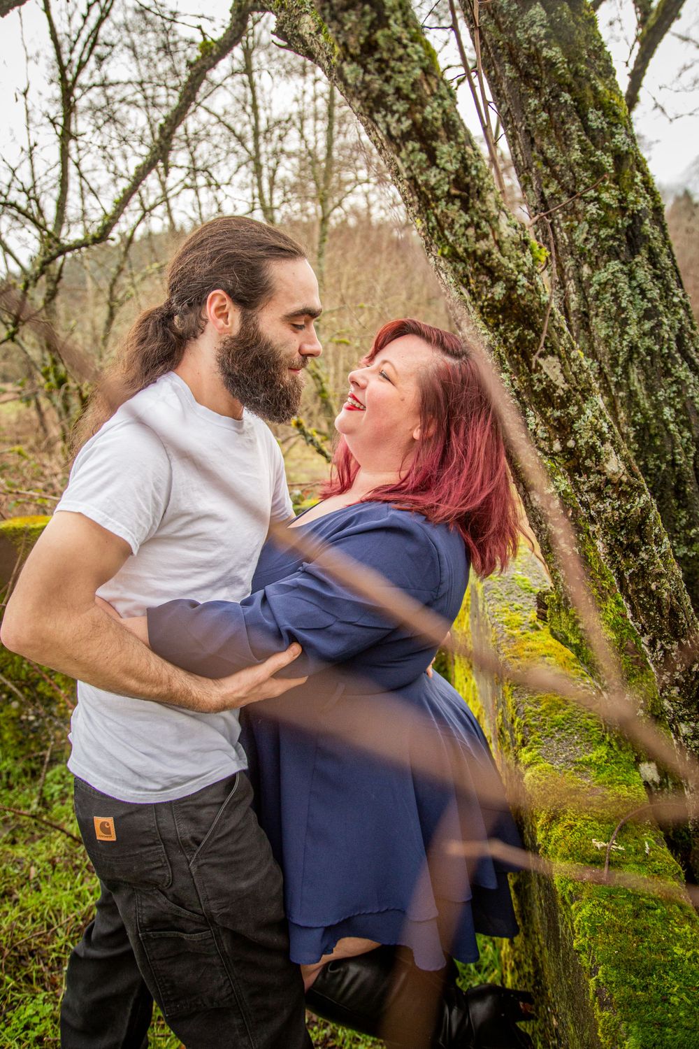 A playful moment captured between two people among tree branches in a natural setting.