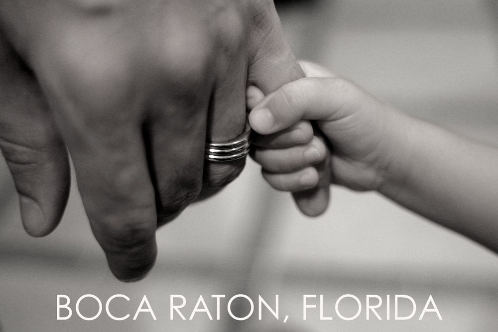 Close-up of adult and child's hands touching with wedding ring visible in Boca Raton, Florida.