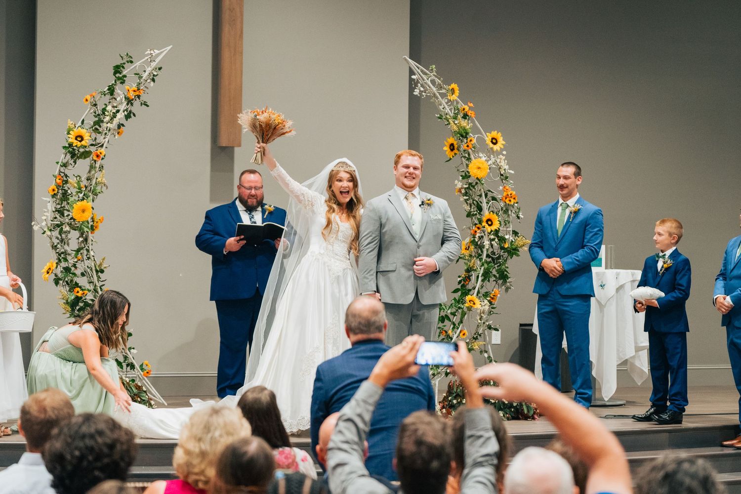 Person holding phone up during wedding ceremony