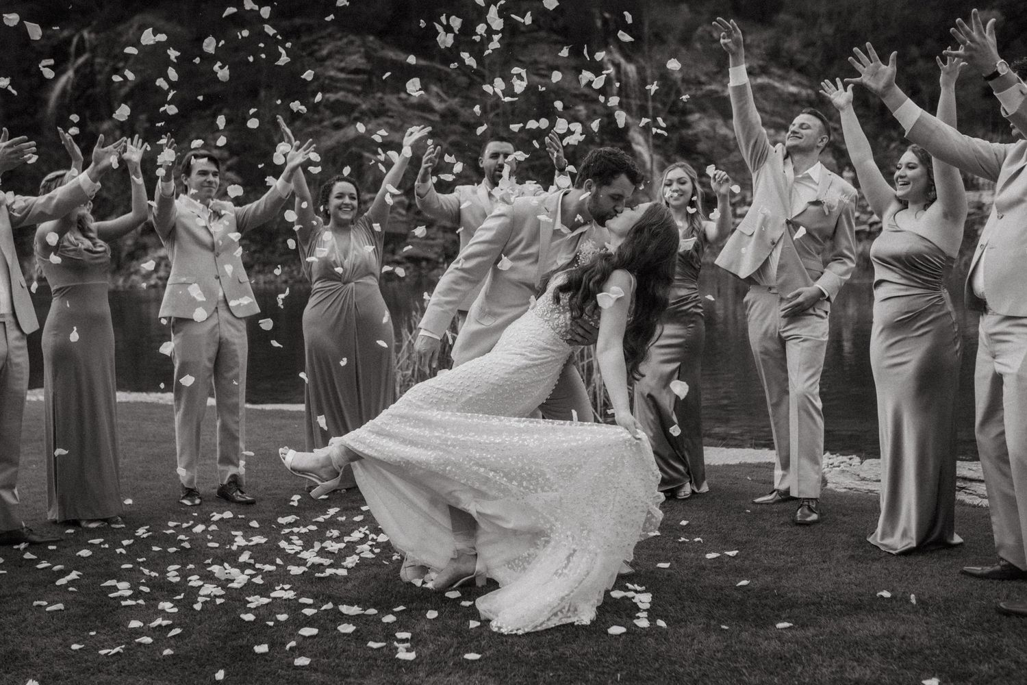 Wedding celebration with guests throwing flower petals during outdoor ceremony.