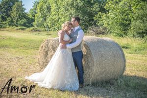 Couple embracing by a hay bale in a sunny summer field.