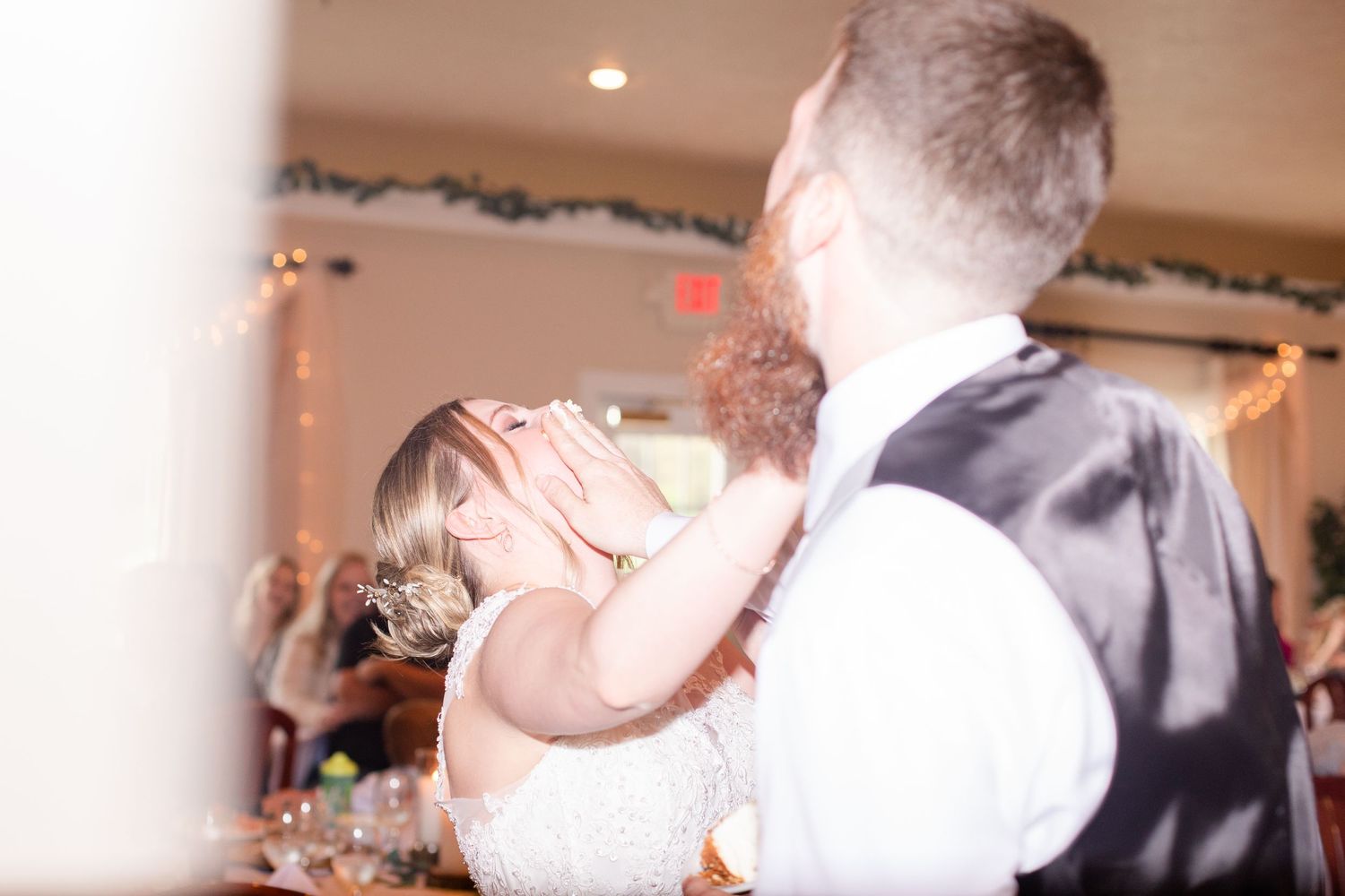 Guests dancing and celebrating at an indoor wedding reception with decorative lighting.