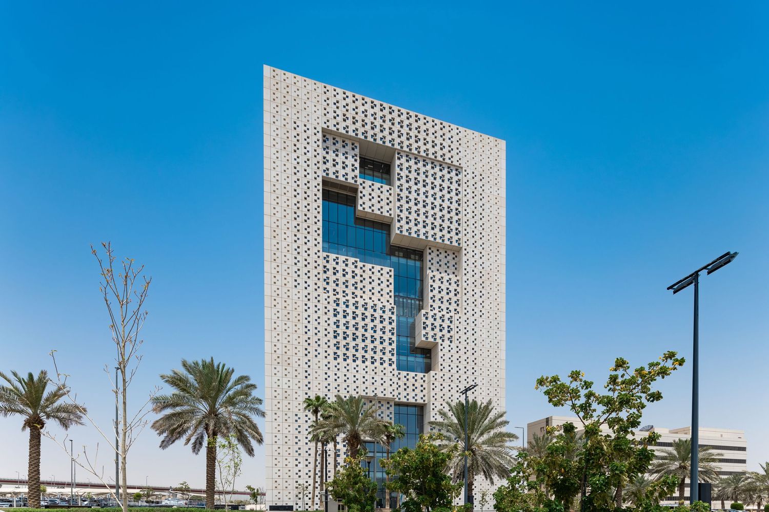 Modern architectural building with unique letter 'F' design cutout against bright blue sky.