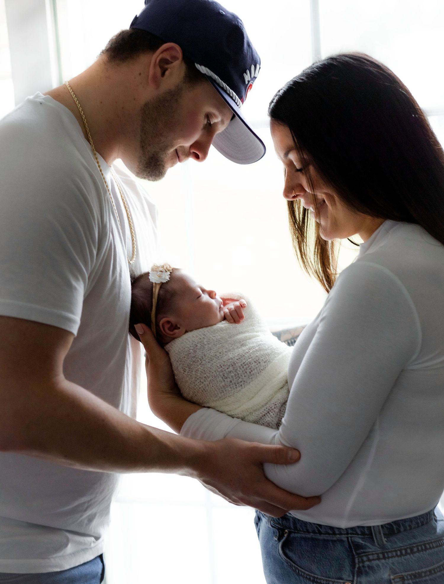 Intimate series of tender moments between parents and newborn in soft window light.