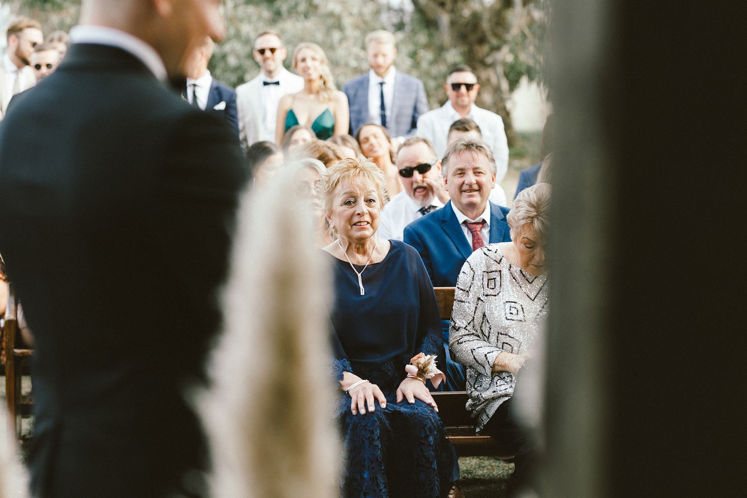 Wedding guests seated outdoors watching an emotional ceremony moment.