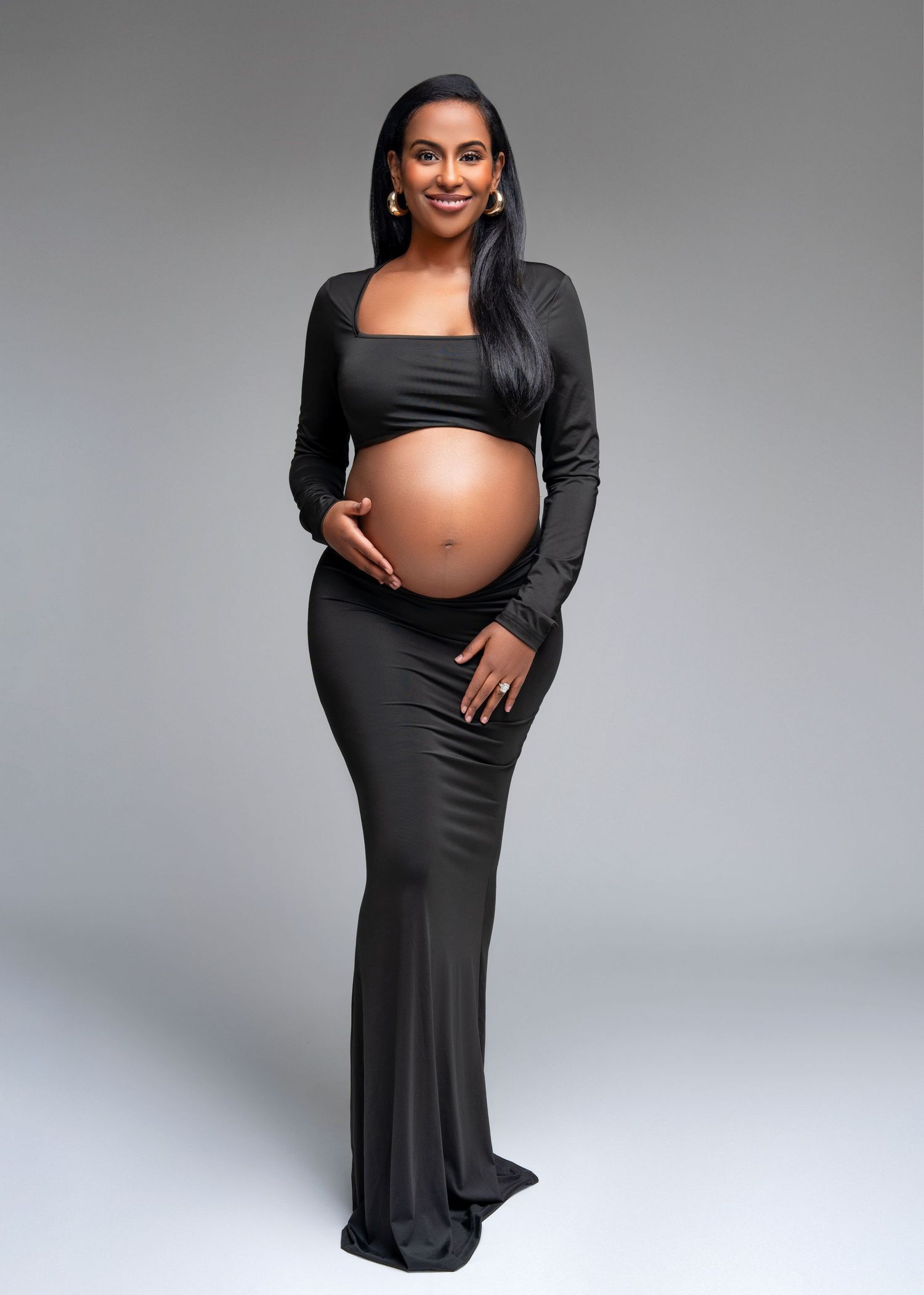 a woman stands smiling in an Minneapolis Minnesota photo studio for maternity portraits