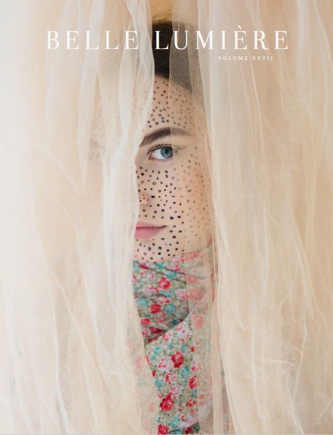 A model hiding amongst layers of nude tulle fabric with a floral wrapped body and intricate facial paintings.