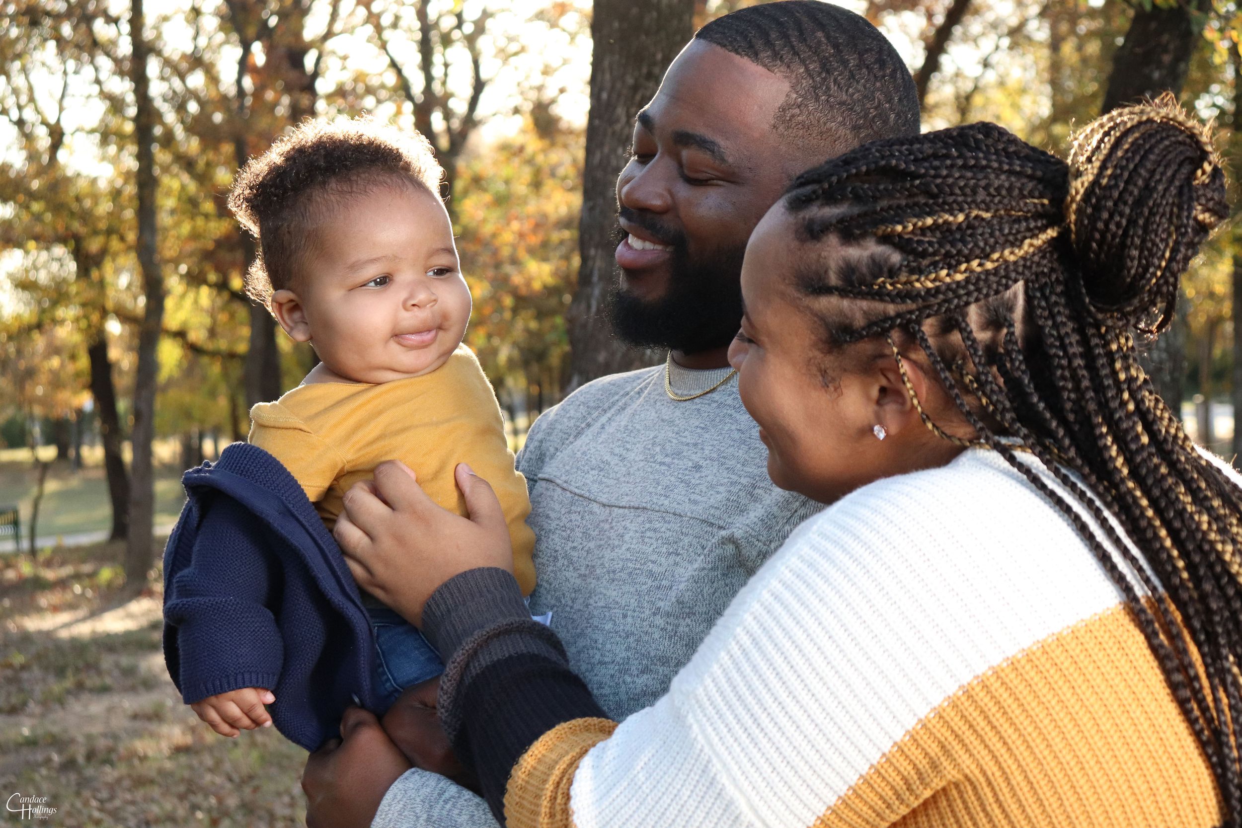 Family bonding together outdoors during autumn with trees in background.