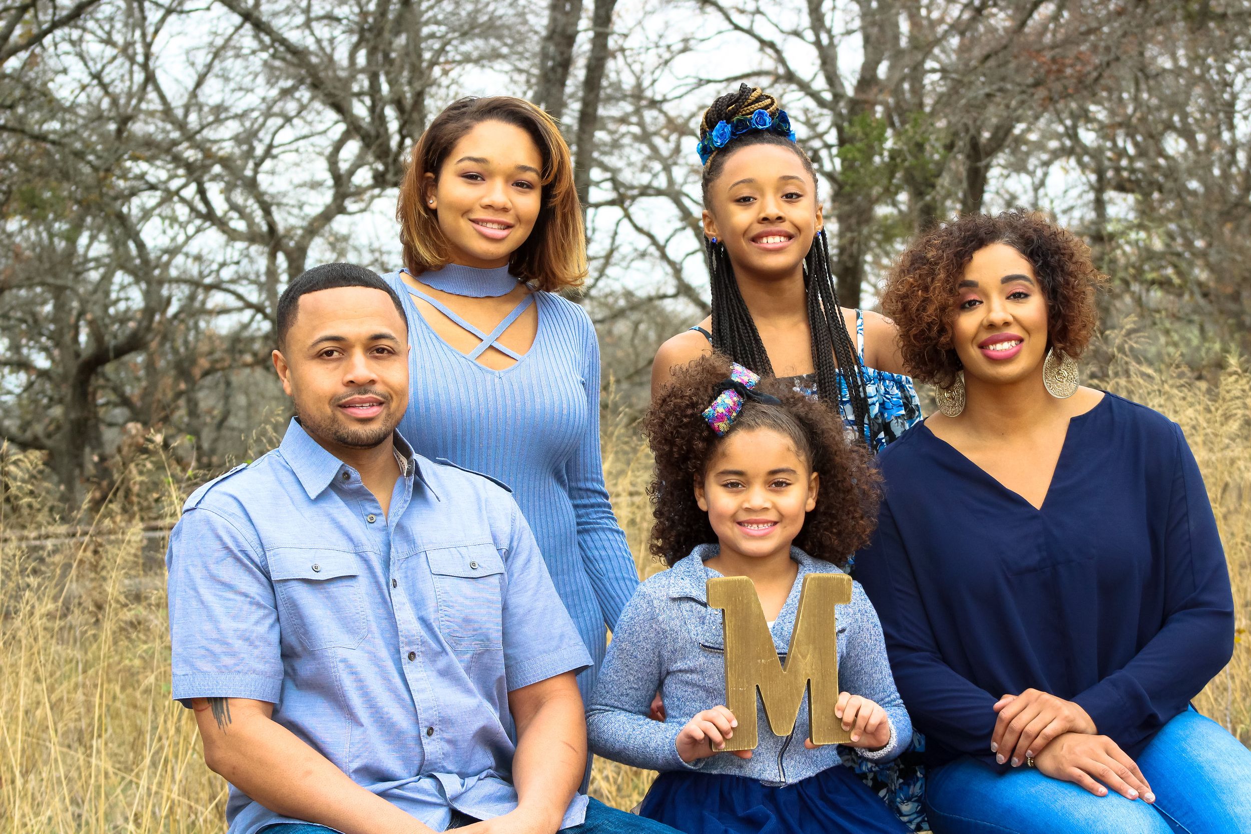 Family sitting together outdoors for casual portrait session.