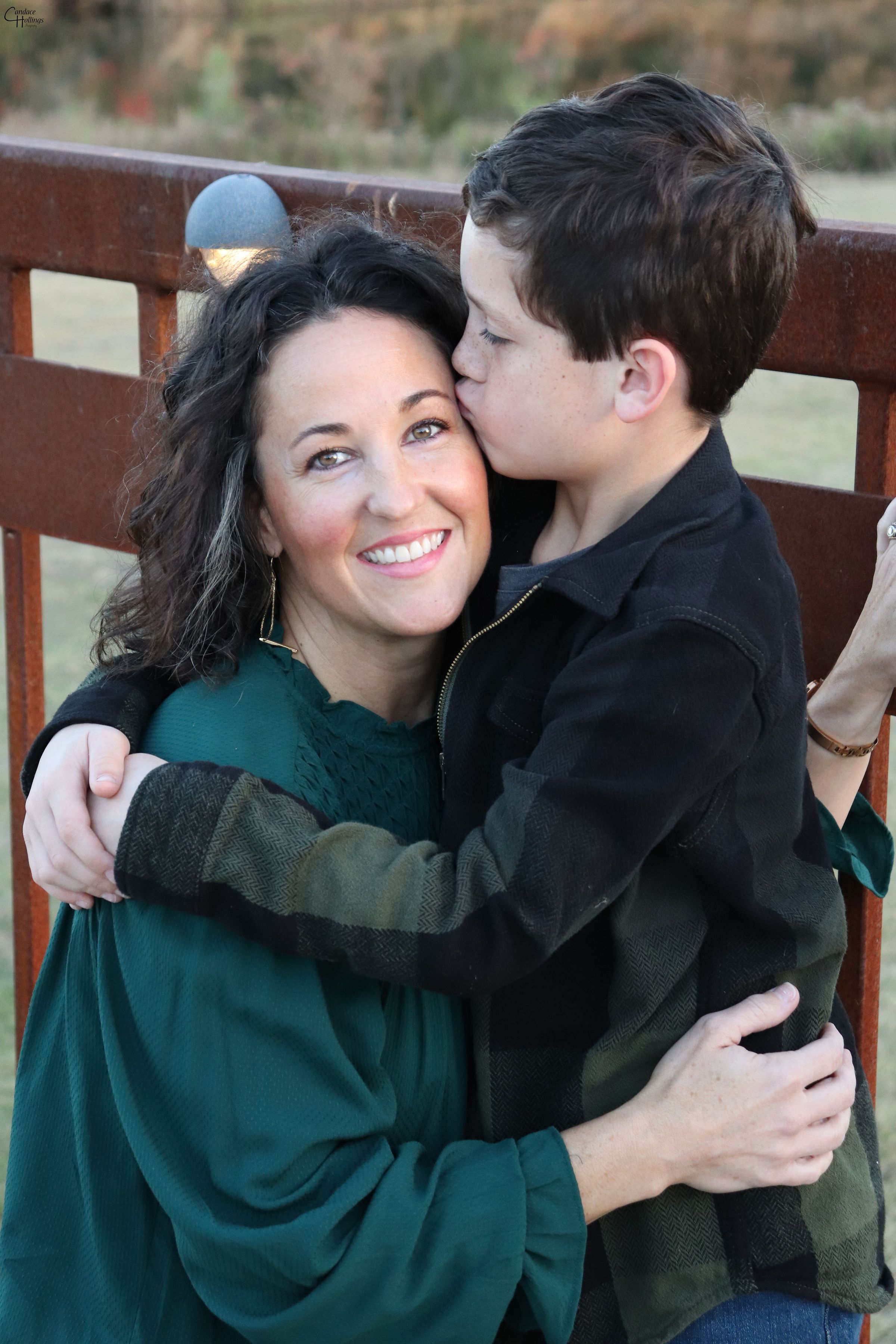 An intimate portrait showing affection between two people on a park bench wearing green and black.