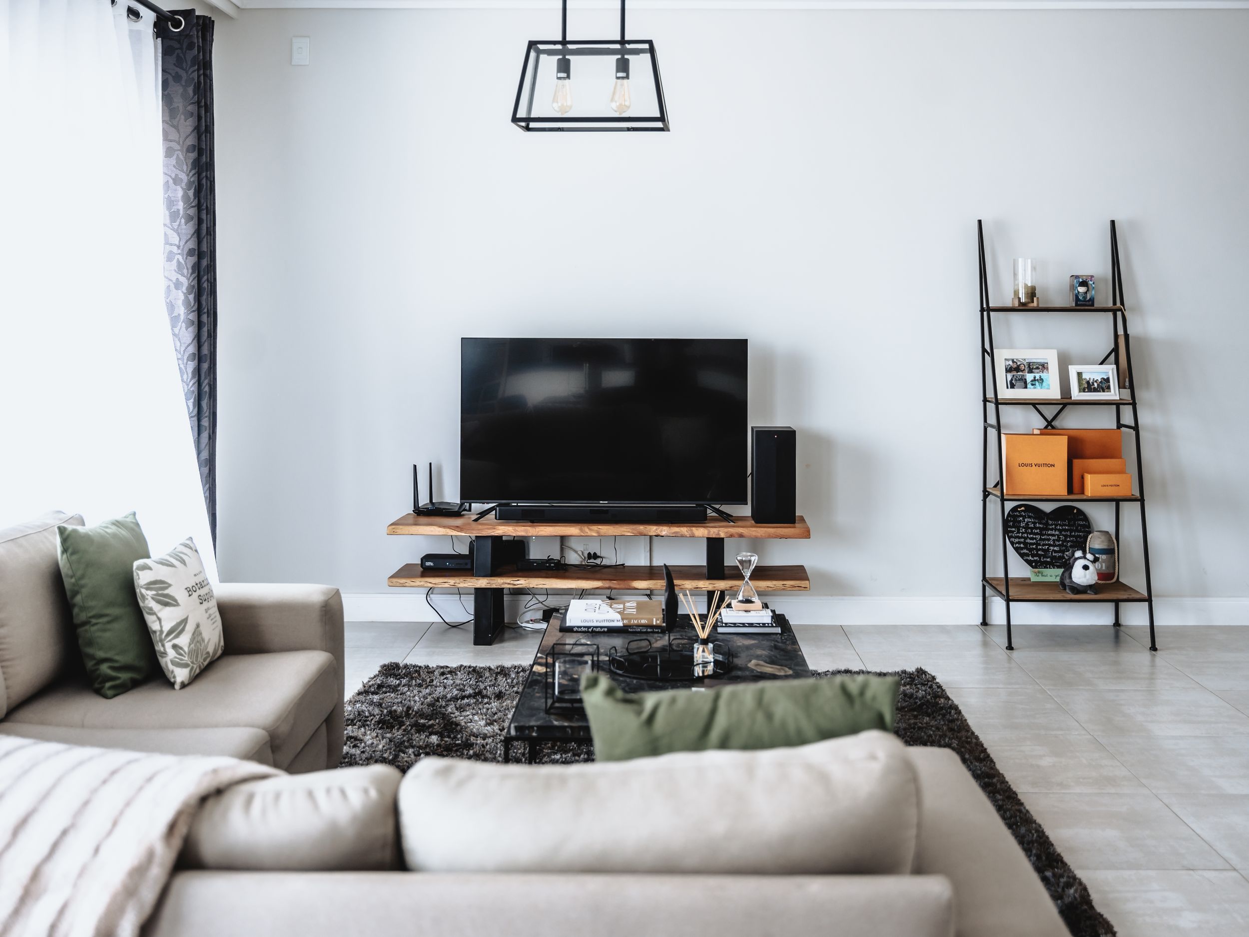 Contemporary living space with flat screen TV, wooden media console and decorative ladder shelf.