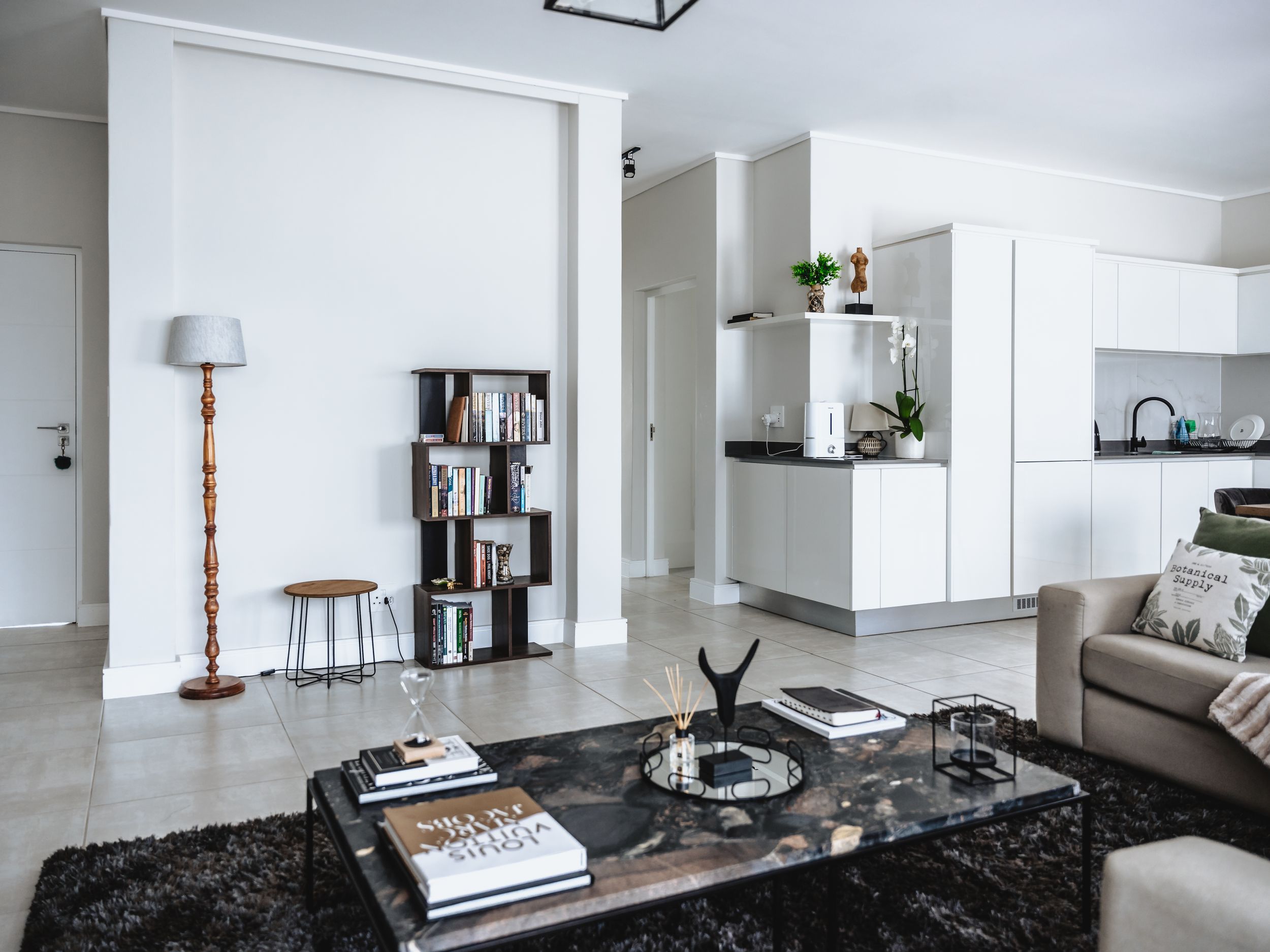 Minimalist living area with black marble coffee table and modern bookshelf divider.