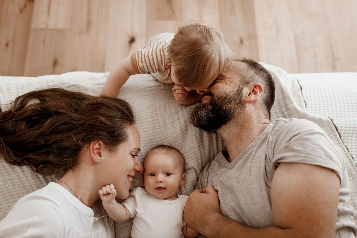 Eine glückliche Familie genießt einen intimen Moment miteinander, während sie bequem auf einem weißen Bett liegt.