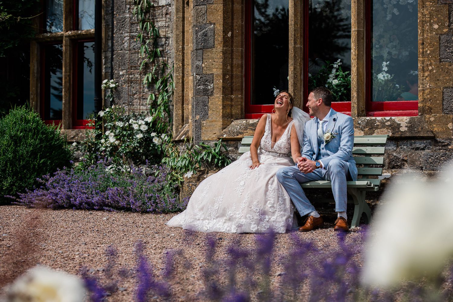 A candid moment of a bride laughing with the groom, at a Tudor style wedding venue in Devon named Huntsham Court.
