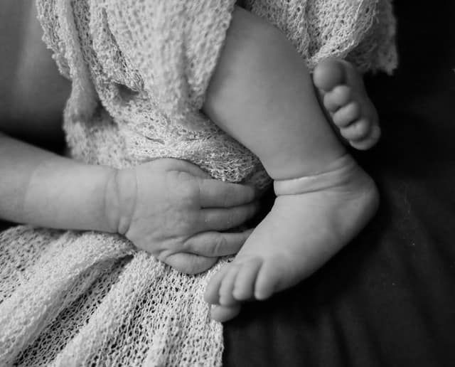 Close-up details of delicate lace fabric and gentle hands in black and white.